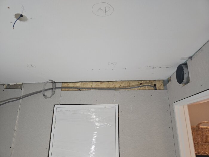 Rum under renovering med taket och en vägg under arbete, exponerade elanordningar och ventilationsrör.