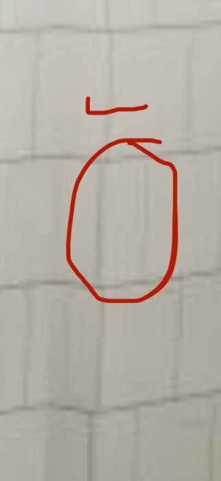 Vägg med rektangulära plattor, en platta inringad i rött, visar ojämn fogning i en källartoalett med granitkeramik.