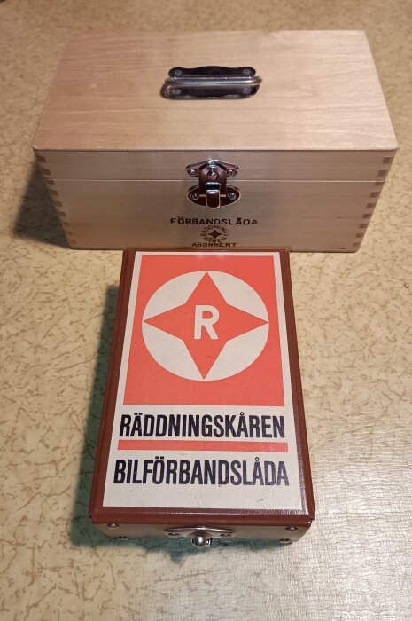 Äldre förbandslådor från Räddningskåren med en vackert sammanfogad trälåda och en orange märkning med bokstaven "R".
