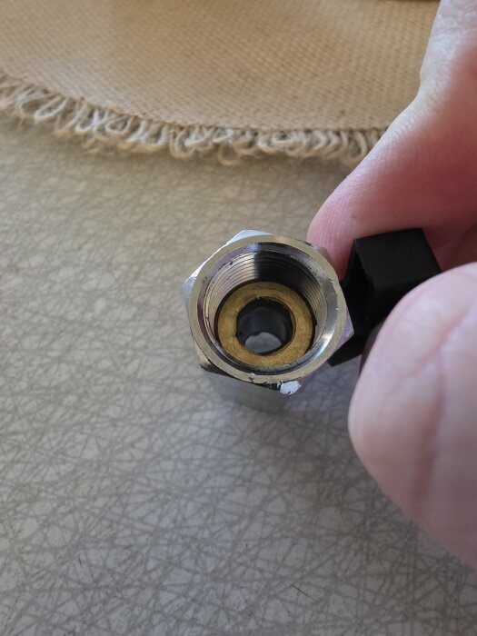 Ventil med borttagen skyddsmutter där en hand demonstrerar, antyder behovet av packning för tätning.