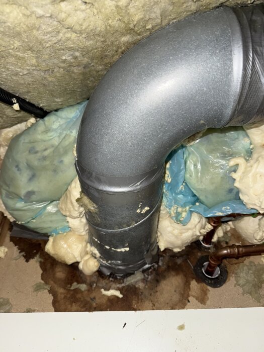 Avluftningsrör från värmepump, synligt kondensvatten på oisolerat metallrör. Isolering och fukt kring golv.