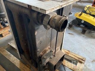 Gammal, rostig maskindel med röranslutning i en verkstadsmiljö på en träpall.