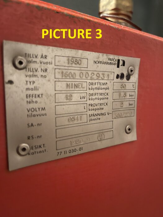 Etikett på en elektrisk värmeanläggning med specifikationer: tillverkningsår 1980, effekt 12 kW, drifttemperatur 80°C, drifttryck 1,5 bar.