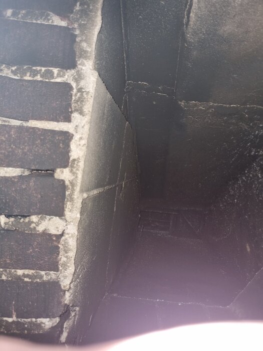 Tegelvägg vid en murstock, eventuell del av en öppen spis eller skorsten, diskussion om att ta bort översta tegelraden för kaminstallation.