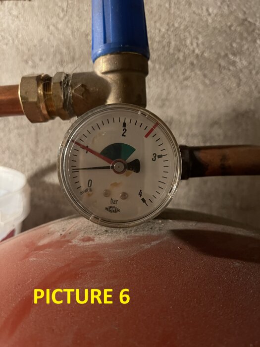 Manometer som visar trycket i ett värmesystem med ett blå anslutningsrör upptill och en kopparledning nedtill, nålen på 1,5 bar.