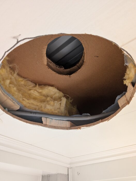 Ett nyligen installerat ventilationshål i ett tak, med isolering runt röret, som har blivit godkänt efter sotarens inspektion.