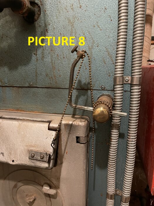 Termostat på vedpanna med kedja och vred för lufttillförsel.