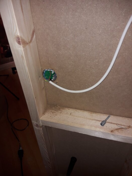 Inbyggd apparatdosa i träkonstruktion med synlig kabel, humoristisk kommentar om att användning av dosan är överdrivet försiktigt.