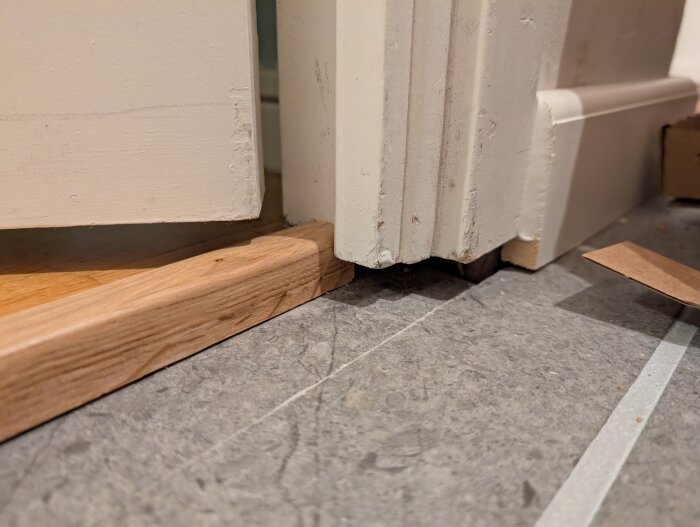 Dörrfoder som inte når ända ned till golvet efter att ett nytt, tunnare golv lagts, med en synlig glipa mellan foder och golv.