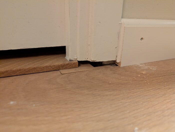 Dörrfoder som är för korta ovanför nytt golv, vilket skapar en synlig glipa mellan foder och golv.