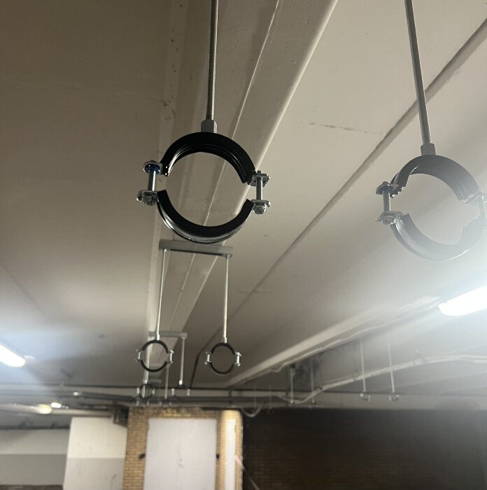 Metallfästen för rörledning monterade i taket i ett garage, i ett renoveringssammanhang.