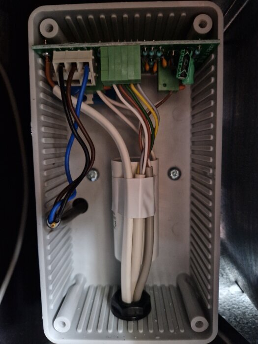 Elektronisk komponentbox med anslutna ledningar och kretskort i ett pågående felsökningsprojekt för en trasig fläkt.