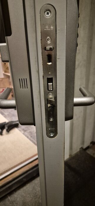 Närbild av ytterdörrens låsmekanism med dörrbleck, skruvar synliga, märket "Yale" ingraverat. Dörrhandtag delvis synligt.