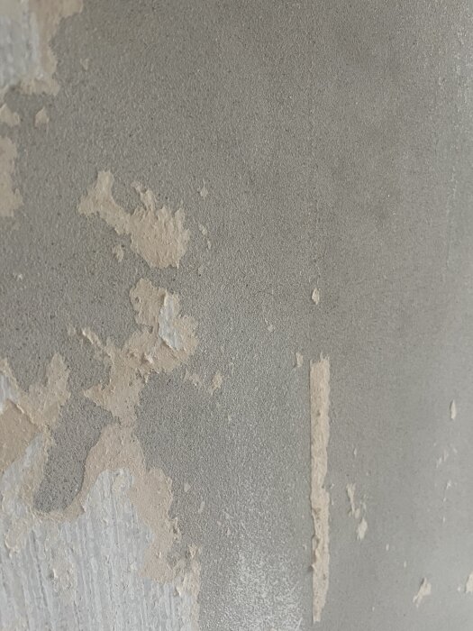 Betongvägg med fläckar av gammal tapet och spackel, del av en renovering där dörröppning ska byggas igen.