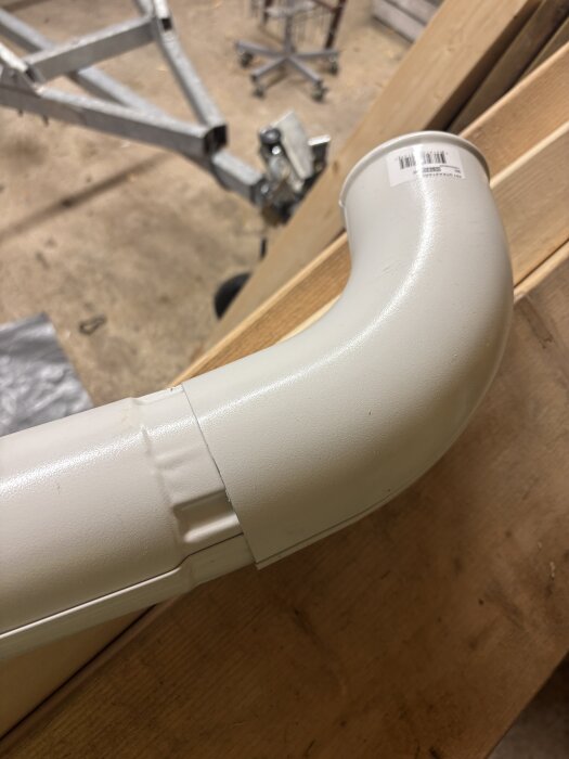 Plaströr med böj på träyta i byggmiljö, del av diskussion om rörkopplingar och installation.