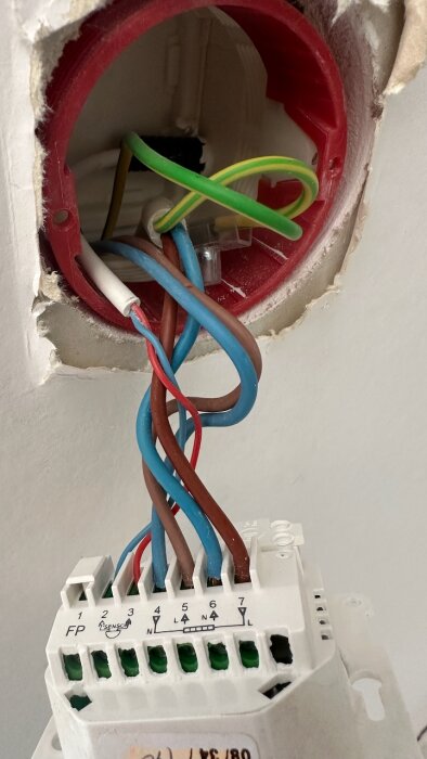 Termostatanslutningar med flera färgade ledningar; gammal installation där ledningar är kopplade till olika plintar märkta från 1 till 7.