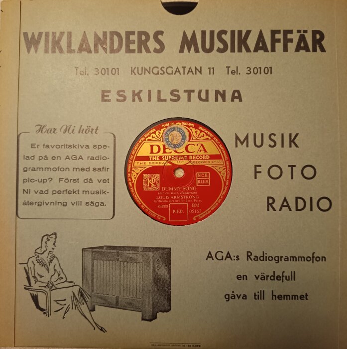 Omslag till en stenkaka från Wiklanders Musikaffär med reklamskrift och skiva med Louis Armstrong.
