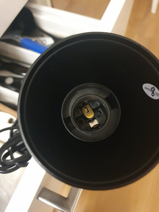 Närbild på insidan av en lampsockel utan lampa, med sladdar synliga bredvid en låda.