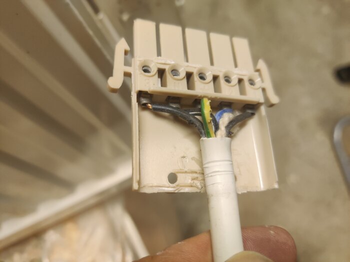 Elektrisk kopplingsbox med flera kablar, inklusive svart, gulgrön och blå, kopplade i olika anslutningar.