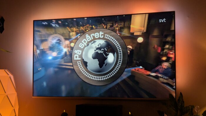 TV-bild från ett svenskt frågesportprogram med glob- och järnvägsmotiv samt texten "På spåret" och logotypen för SVT.