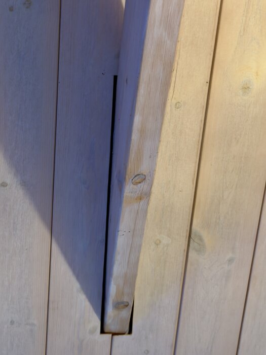 Snett foto av ett träbjälklag med synligt mellanrum mellan bjälke och takpanel, i ett nyköpt hus.