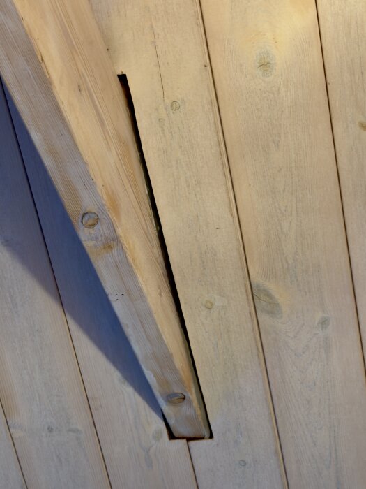 Mellanrum mellan takstol och träplankor i taket som behöver fixas.