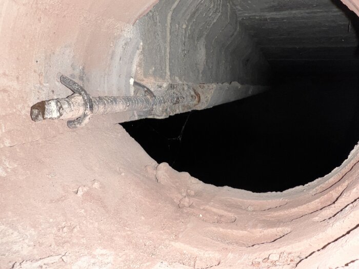 Rostig armeringsjärn synligt i skadad betongkonstruktion med tydlig sprickbildning.