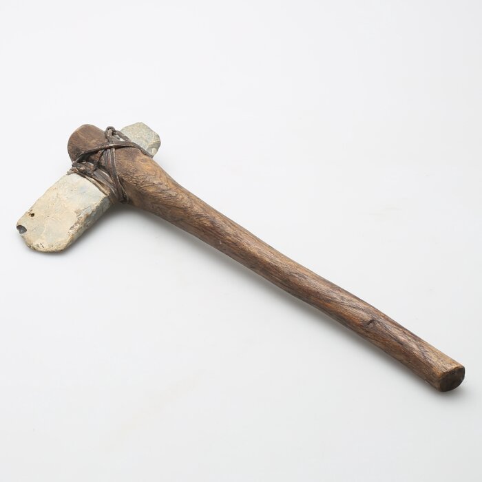 Handgjord yxa med stenblad och träskaft, bunden med snöre.