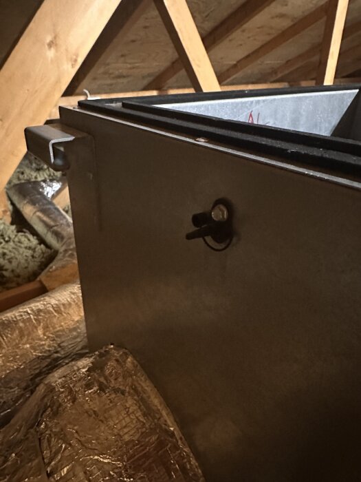 Ventilationsaggregat Östberg Heru 130s i vindsutrymme med en anslutning för slang synlig på utsidan av enheten.