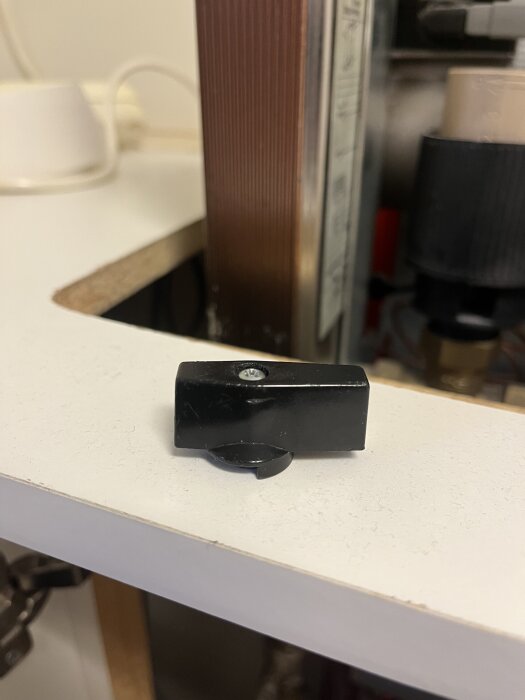 Svart ventilvred placerat på en vit yta, bredvid en fjärrvärmecentral.