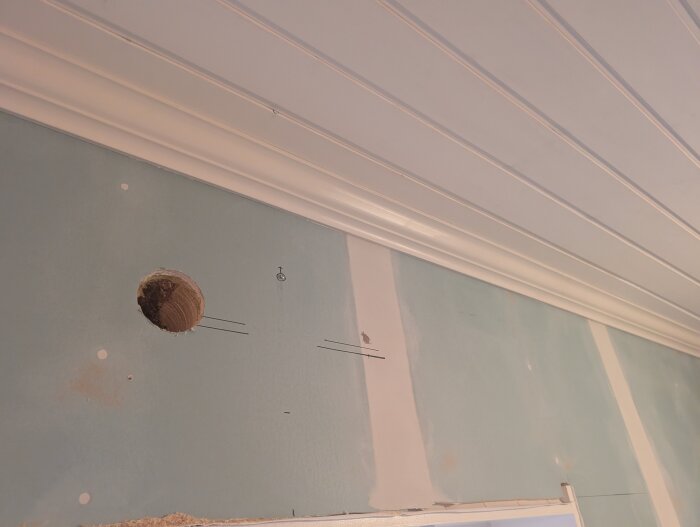 Hål i vägg med träpanel i taket, borret träffade en spik.