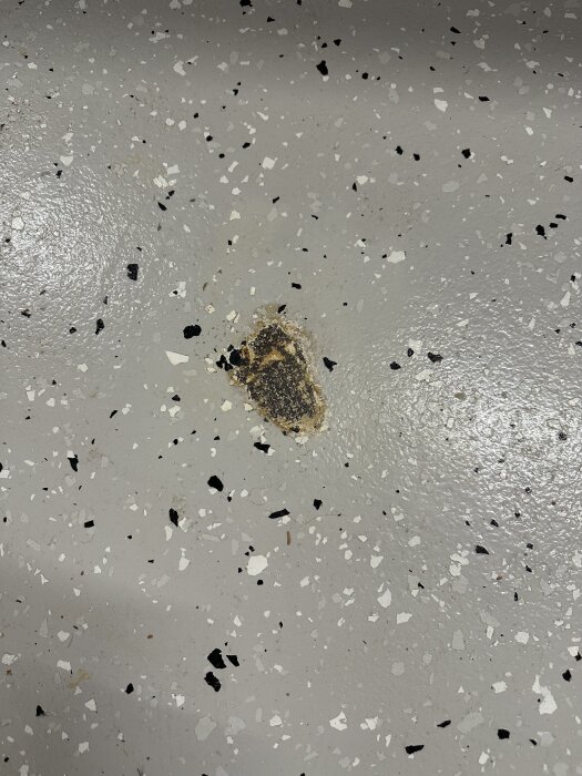Fläck på betonggolv med avflagning av tvåkomponentsfärg från Biltema, lossnar på grund av okänt material under ytan.