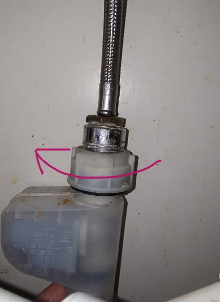 Plastmutter och förkromad bussning med rosa pil som visar riktning för att lossa muttern.