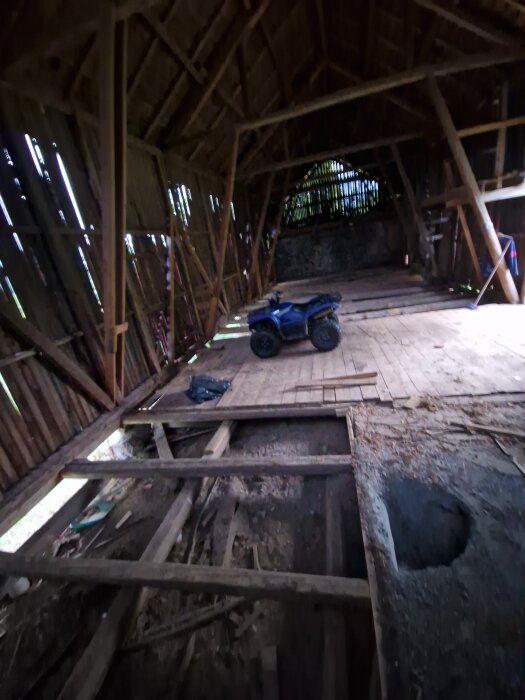 Renoveringsprojekt i en loge, grävd grop för gjutning av golv, träbalkar och en fyrhjuling synlig.