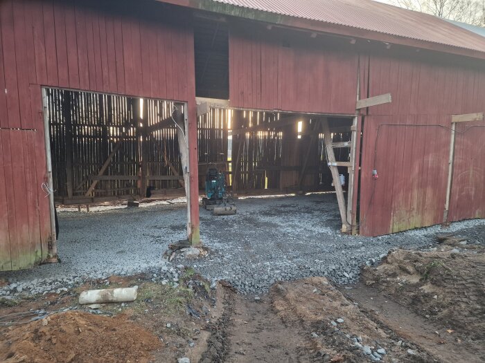 Renovering av gammal loge, golvet är fylld med grus och förbereds för gjutning. En grävmaskin står i den öppna dörröppningen.