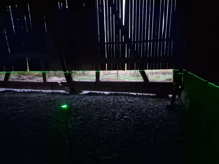 Interiör av loge under renovering med gröna laserlinjer projicerade längs väggen och grusgolvet, som del av golvutjämning och planering.