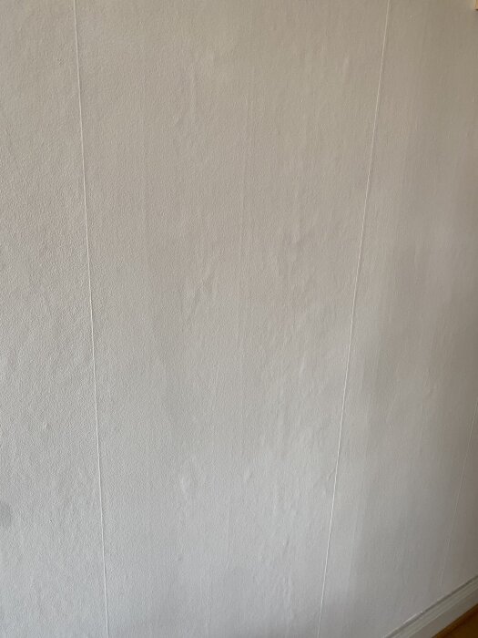 Vägg med ojämnheter och skuggor, potentiellt kräver renoveringstapet eller bredspackling för att jämna ut ytan.