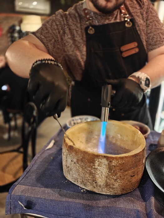 Kock flamberar carbonara i en osthjul med blåslampa.