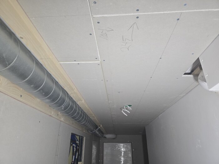 Gipstak i källarkorridor innan målning, spirorör längs väggen och glesning. Förberett för nätverksuttag och eltrådar vid spotlights.