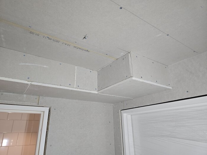 Gipstak och väggvinkel i en källarkorridor under konstruktion, med synliga skruvar och hål innan ytskikten installeras.