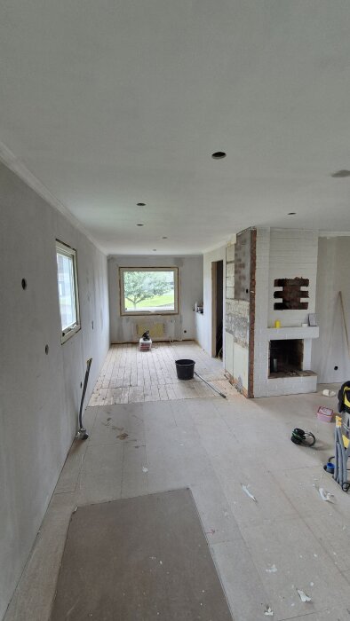 Renoverat rum med nymålat tak, installation av tilluftsspjäll påbörjad. Takbelysning saknas, synliga golvbrädor och verktyg på golvet.