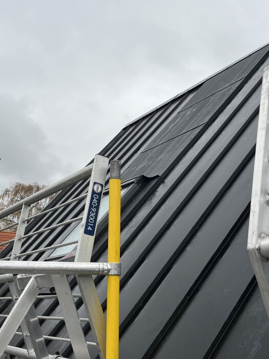 Tak med Plannja trend klicktak och installerat takfönster, omringat av en byggställning under molnig himmel.