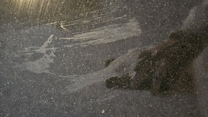 Granitskiva i köket med matta fläckar orsakade av superlim, trots försök att rengöra med olika metoder. Ytan ser repad och ojämn ut.