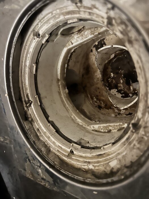 Närbild av ett smutsigt och trasigt avlopp utan vattenlås i ett tvättrum, med skador på insatsen.