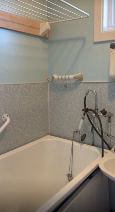 Badkar med laminatväggar och gammaldags blandare i ett badrum från ett 30-talshus, renoverat mellan 50- och 80-tal.