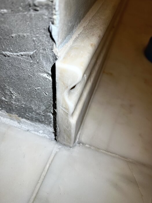 Närbild på slipad marmorsockel med synliga repor och virvlar, samt runda kanter som ser ojämna och ofärdiga ut.