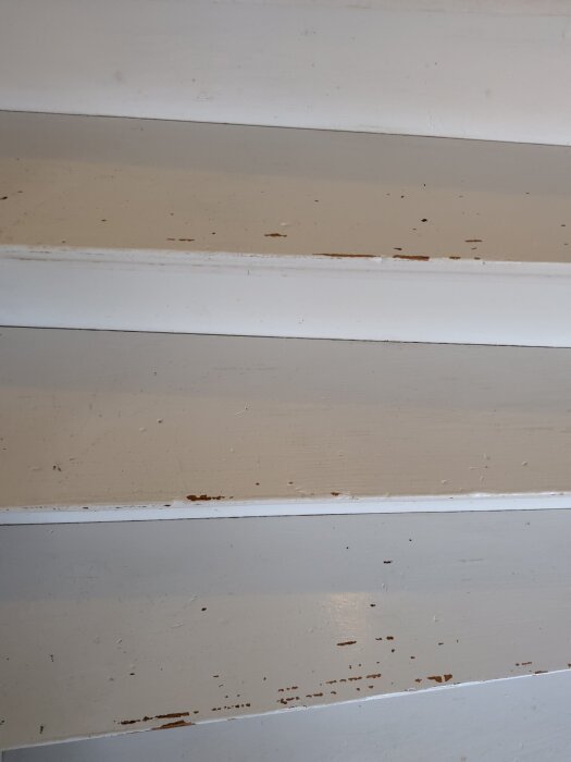 Slitna trägolvbrädor med borttagen matta och kvarvarande fläckar av lim.