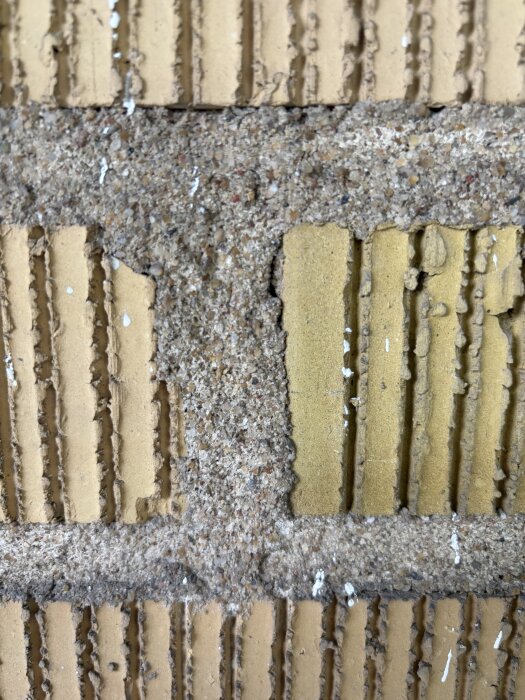 Närbild av tegelvägg från sent 50-tal med porösa fogar fyllda med sandhaltigt murbruk, med tydliga håligheter i fogarna.