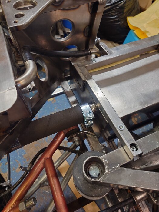 Svart slang med metallklämma monterad i maskindelars fäste.