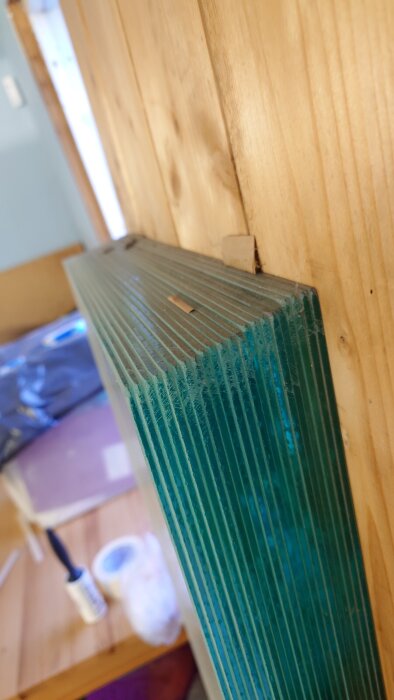 Staplade glasrutor i isolerat garage, klistrade ihop på grund av fukt, med trävägg i bakgrunden.